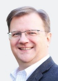 A person wearing glasses and a suit

Description automatically generated