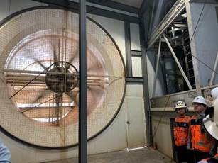 A person standing in front of a large fan

Description automatically generated