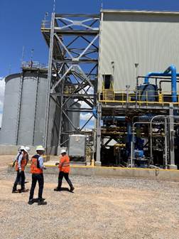 A group of people walking in front of a factory

Description automatically generated